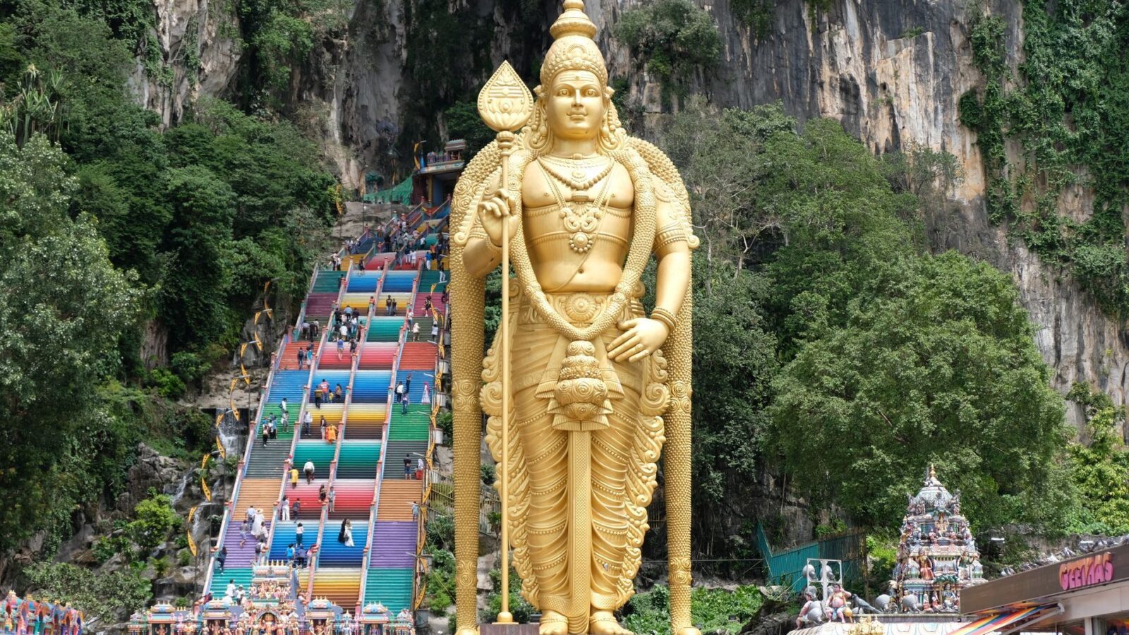Majestic golden Lord Murugan statue stands before vibrant Batu Caves entrance in Selangor, Malaysia